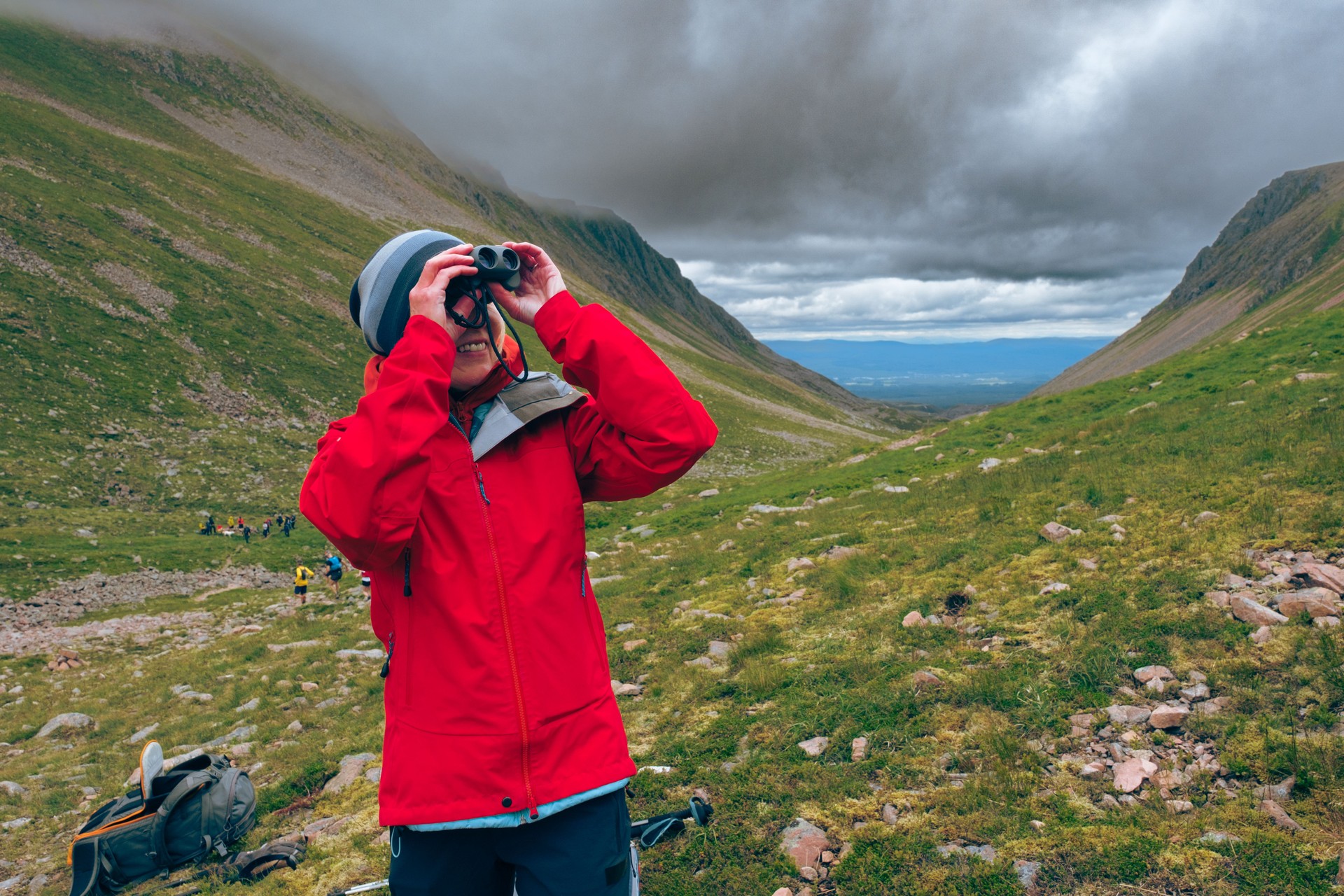 Senior woman looking through binoculars at Lairig Ghru, Cairngorms, Scotland